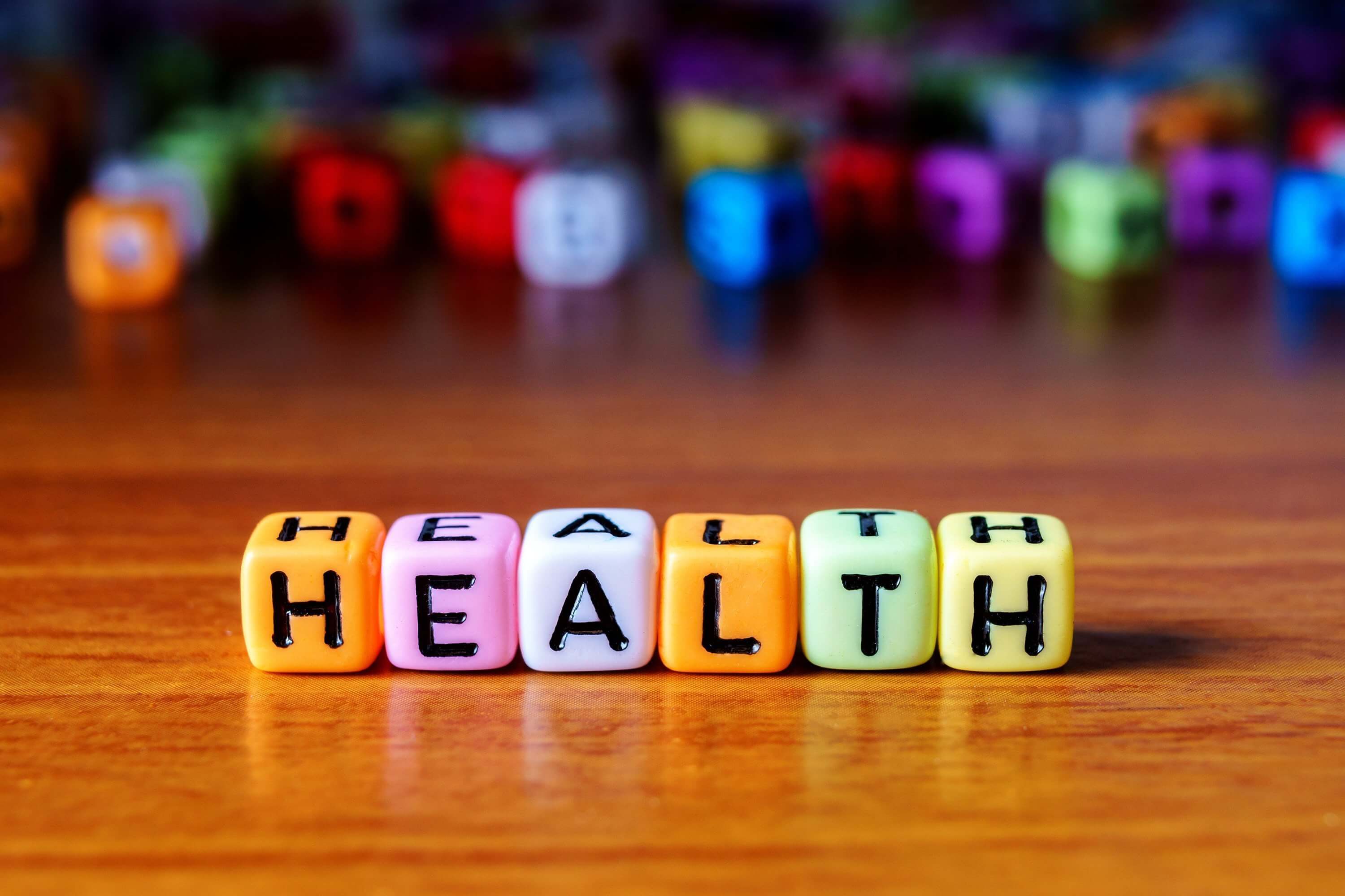 Word HEALTH spelled with colorful beads on wooden table. Read on for tips to improve patient health literacy.