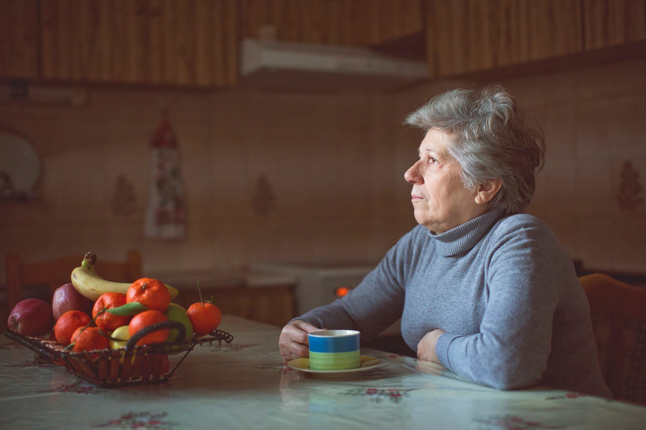 Elderly woman sitting at table. This article relates to solo agers.